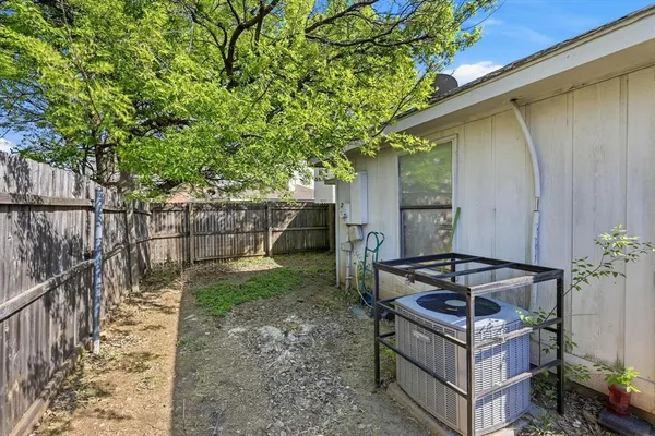a backyard of a house with wooden fence and large trees