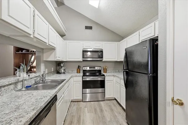 a kitchen with stainless steel appliances granite countertop a refrigerator a stove a sink and a microwave