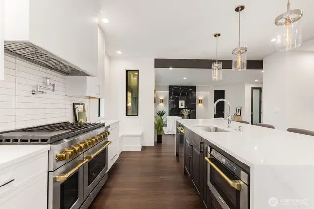 a large kitchen with stainless steel appliances a stove a sink dishwasher and a refrigerator with wooden floor