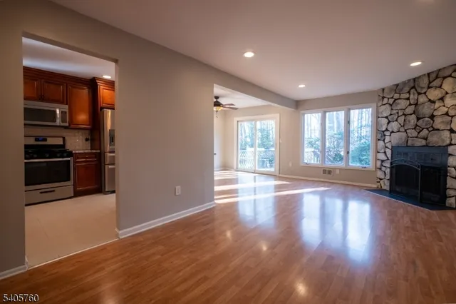 an empty room with wooden floor fireplace and windows