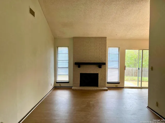 a view of an empty room with a fireplace and a window