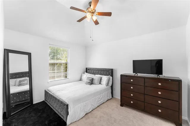 a bedroom with a bed and a flat tv screen on a dresser