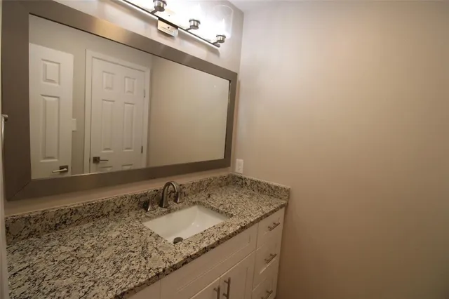 a bathroom with a granite countertop sink and a mirror