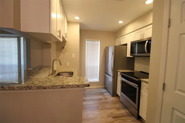 a kitchen with stainless steel appliances granite countertop a refrigerator a stove and a sink