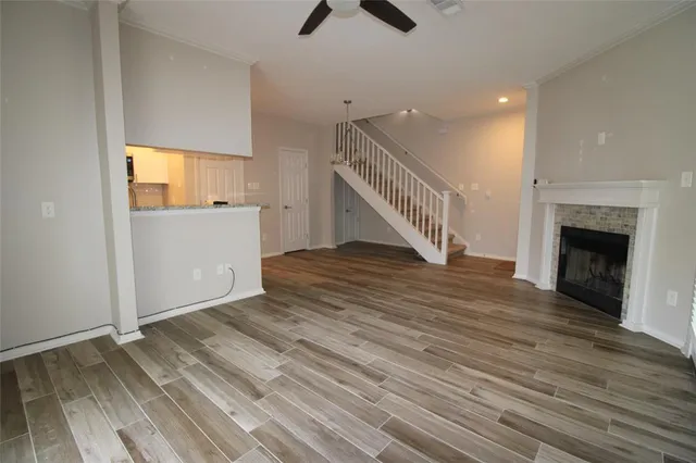a view of an empty room with wooden floor a ceiling fan and a window