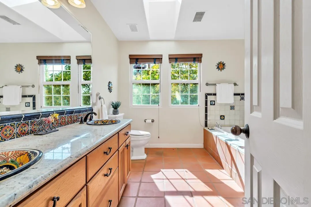 15127 Sycamore Canyon Road Poway, CA 92064 - Photo 31 of 47 a bathroom with a granite countertop sink a large mirror a bathtub and next to a window