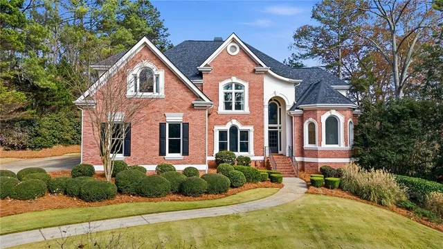 a front view of a house with a yard and potted plants