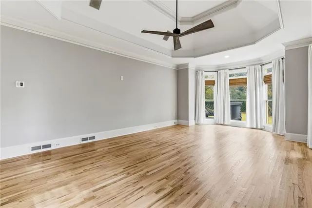 an empty room with windows and chandelier fan