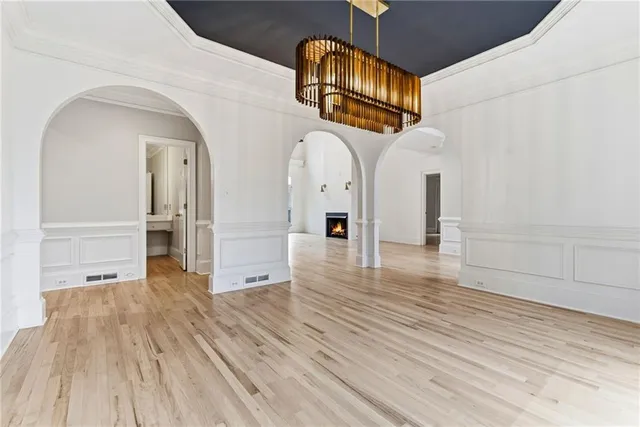 a view of an empty room with wooden floor and a fireplace