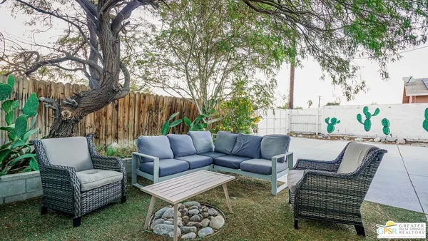 a view of a patio with couches and a fire pit and large tree