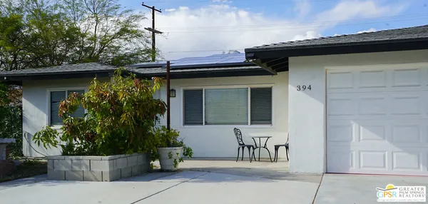 a view of a house with a small yard and potted plants
