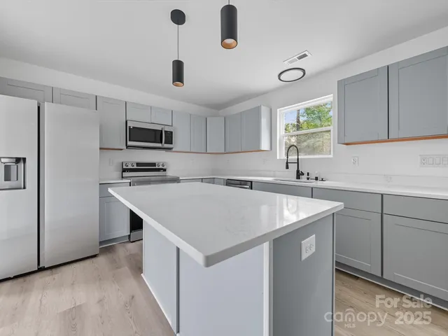 a kitchen with kitchen island a sink appliances and cabinets