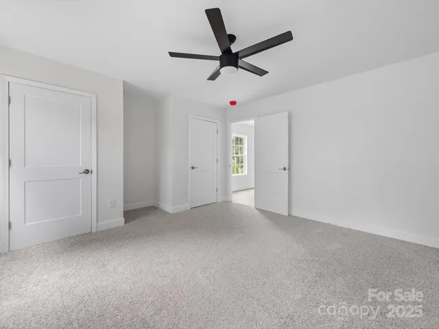 an empty room with ceiling fan and windows