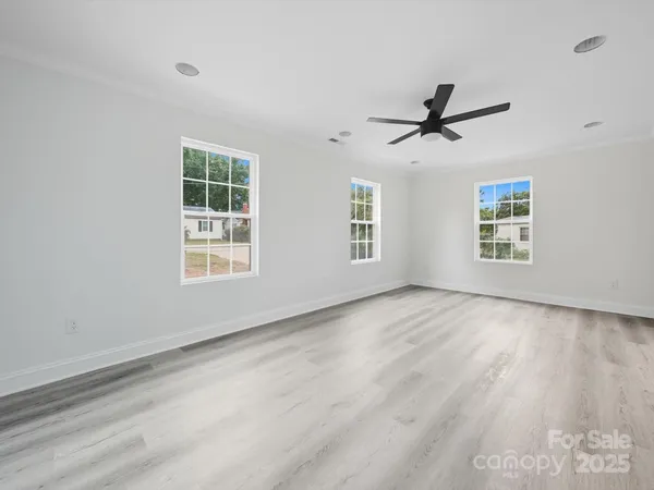 a view of empty room with wooden floor and ceiling fan