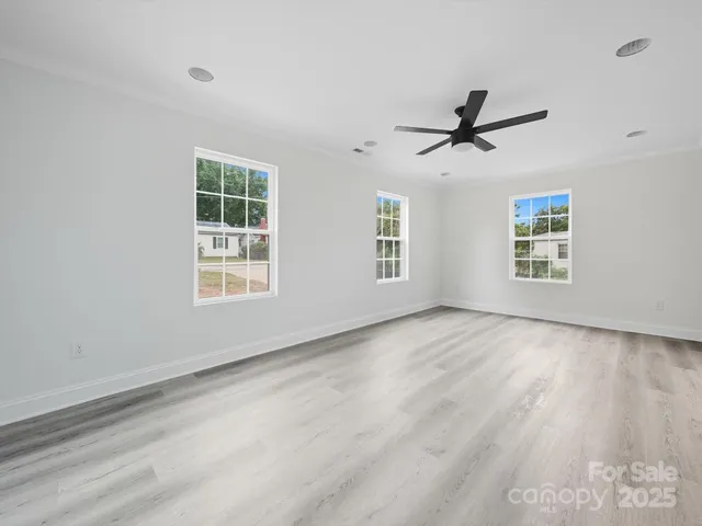 a view of empty room with wooden floor and ceiling fan
