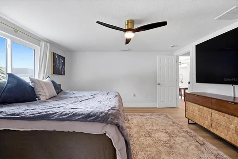 a bedroom with a large bed a flat tv screen and a dresser