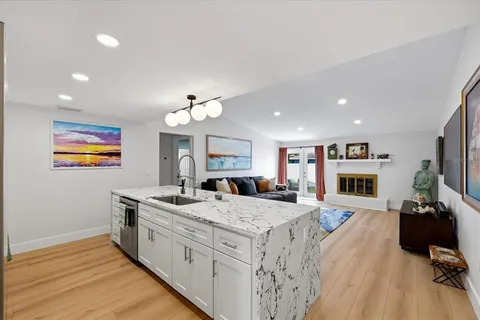a large kitchen with stainless steel appliances granite countertop a sink dishwasher a dining table and chairs with wooden floor
