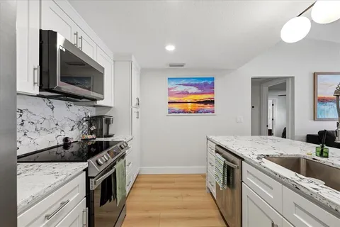 a kitchen with stainless steel appliances granite countertop a stove a sink and a microwave
