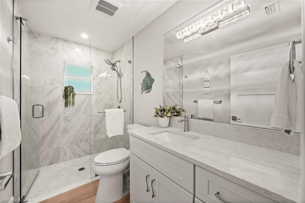 1925 Imperial Golf Course Boulevard Naples, FL 34110 - Photo 29 of 45 A beautifully updated guest bath featuring a frameless glass shower, marble-look tile, and a sleek quartz vanity, refined, bright, and spa-inspired.