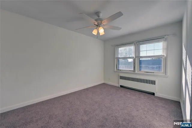 an empty room with chandelier fan and windows