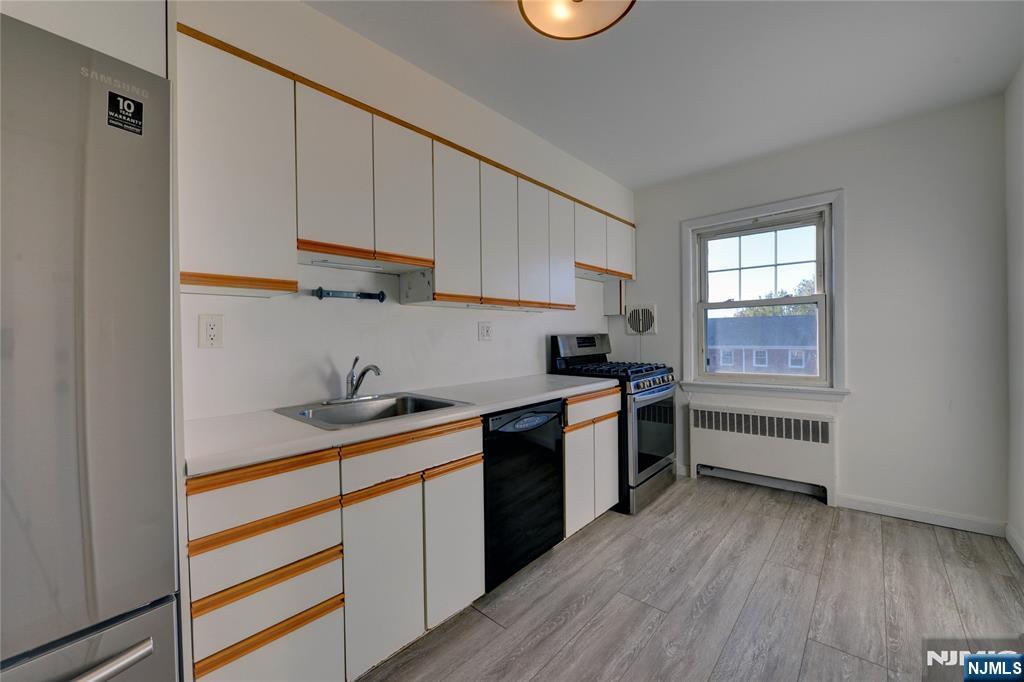 255 Bogert Road, Unit 2A River Edge, NJ 07661 - Photo 7 of 25 a kitchen with a sink a stove and cabinets