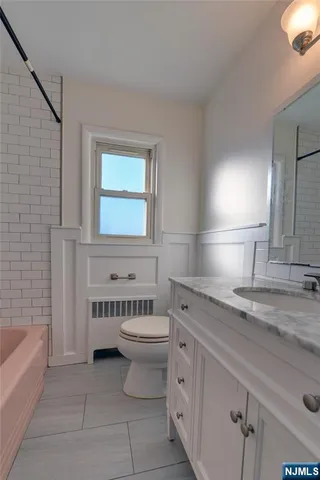 a bathroom with a granite countertop sink a toilet and bathtub
