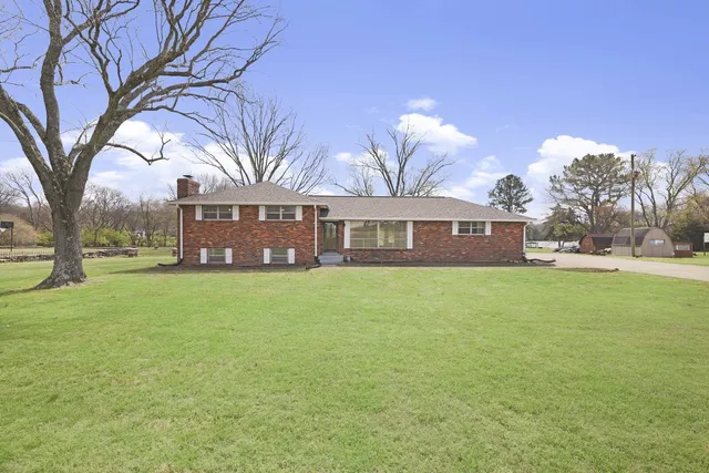 a front view of a house with a garden and trees