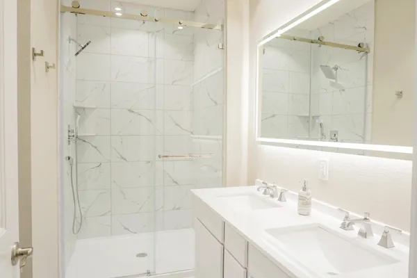 a bathroom with a sink shower and a mirror