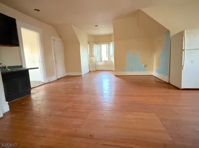 a view of an empty room with window and wooden floor