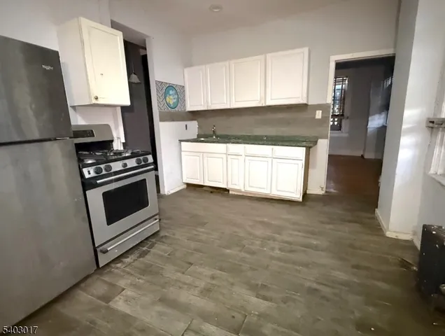 a kitchen with granite countertop a stove a sink and a refrigerator