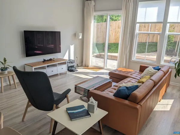 a living room with furniture a flat screen tv and a large window