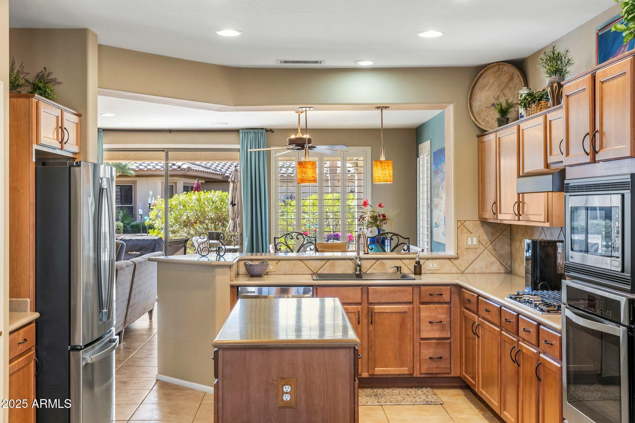 20139 North Rawhide Way Surprise, AZ 85387 - Photo 14 of 30 a kitchen with stainless steel appliances granite countertop a refrigerator a sink dishwasher a stove and a dining table with wooden floor