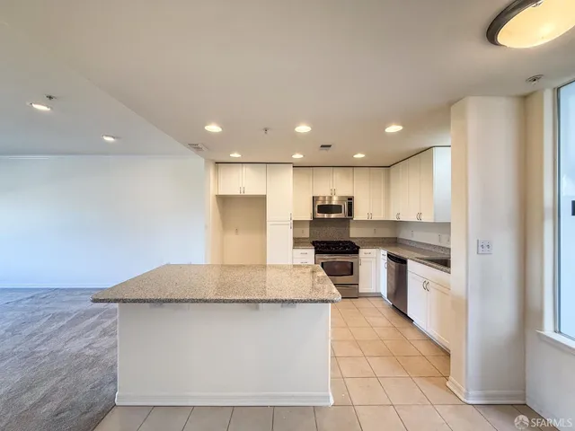 a large kitchen with a large counter top stainless steel appliances and cabinets