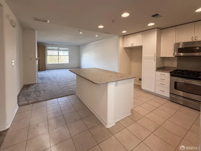 a kitchen with kitchen island granite countertop a stove a sink and a refrigerator