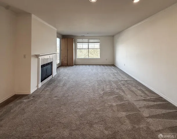 an empty room with windows and fireplace