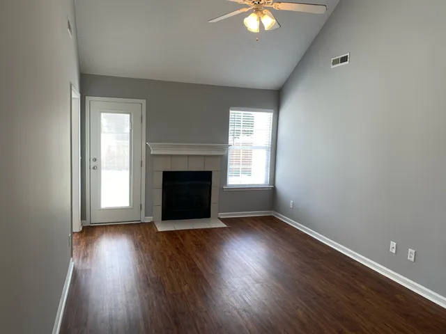 an empty room with wooden floor a fireplace and windows