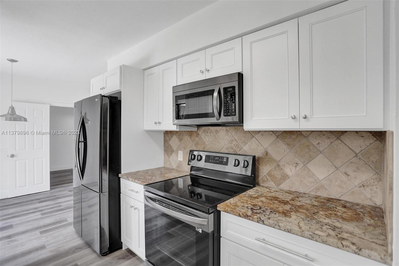 6842 Northwest 13th Street Plantation, FL 33313 - Photo 12 of 33 a kitchen with granite countertop a stove microwave and refrigerator