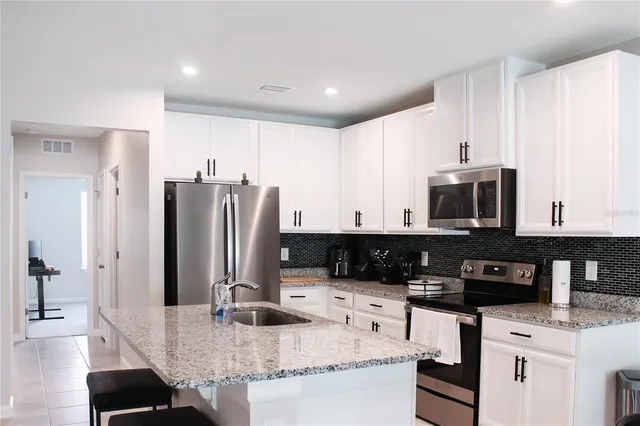 a kitchen with stainless steel appliances granite countertop a sink and a refrigerator