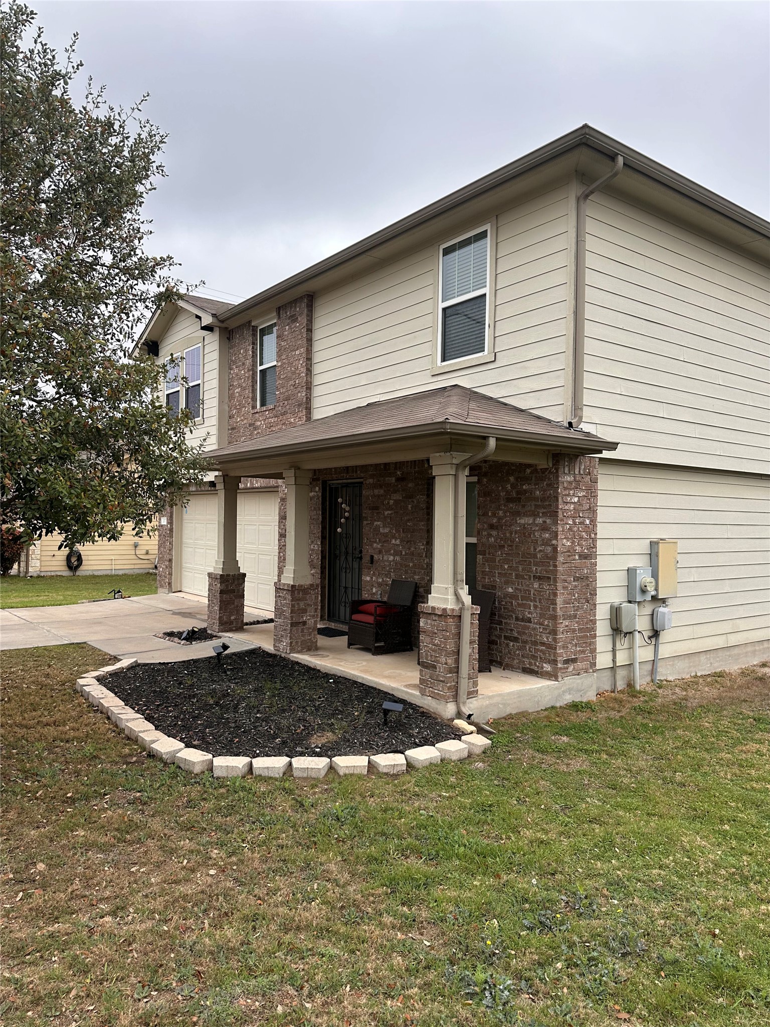 207 Liard River Road Hutto, TX 78634 - Photo 2 of 25 View of front of home with a front yard, brick siding, a garage, concrete driveway, and covered porch