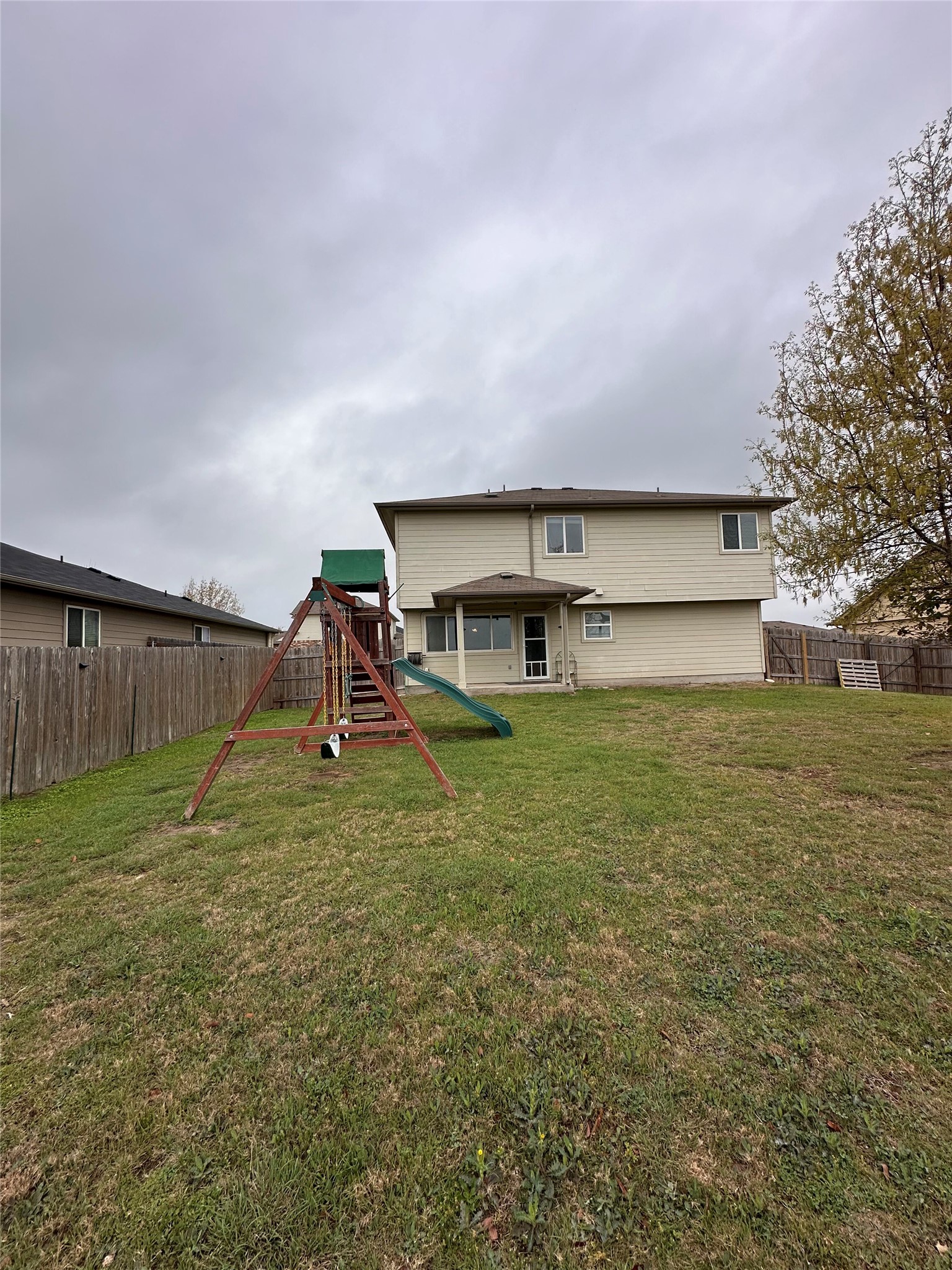 207 Liard River Road Hutto, TX 78634 - Photo 25 of 25 Back of property with a fenced backyard, a playground, and a patio