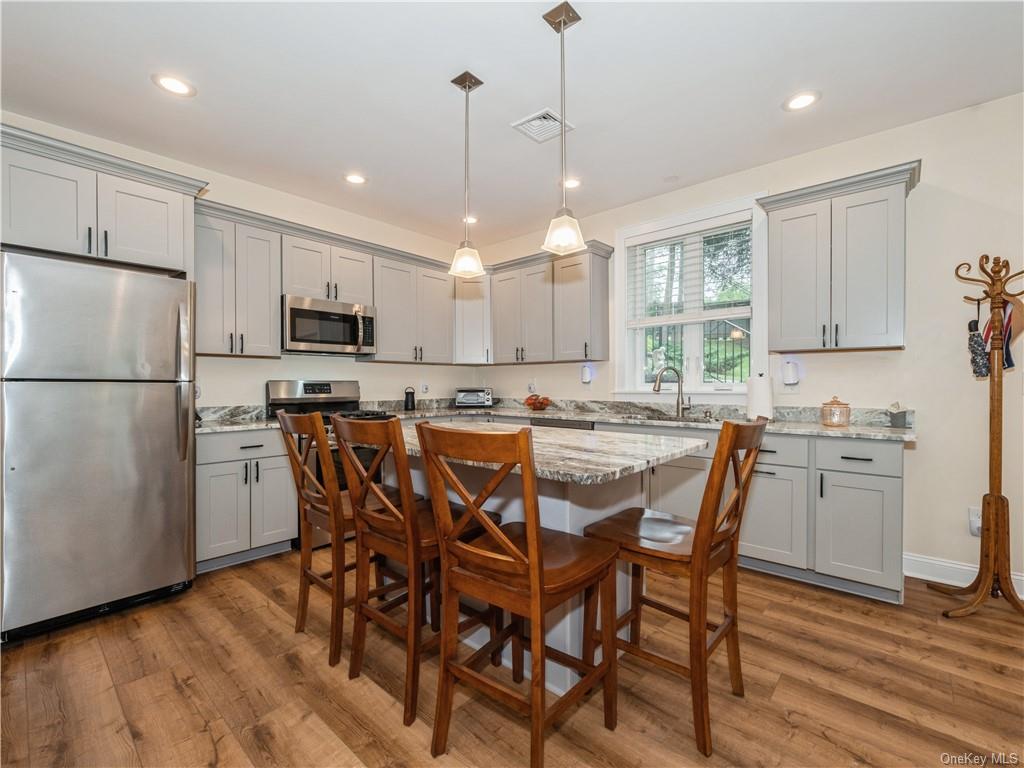 6-8 Wilbur Road Pleasant Valley, NY 12569 - Photo 11 of 36 Kitchen featuring appliances with stainless steel finishes, a kitchen breakfast bar, a kitchen island, light hardwood / wood-style flooring, and light stone counters
