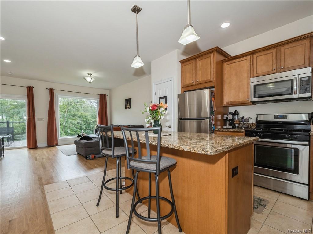 6-8 Wilbur Road Pleasant Valley, NY 12569 - Photo 27 of 36 Kitchen featuring stainless steel appliances, hanging light fixtures, a kitchen breakfast bar, light hardwood / wood-style floors, and light stone counters