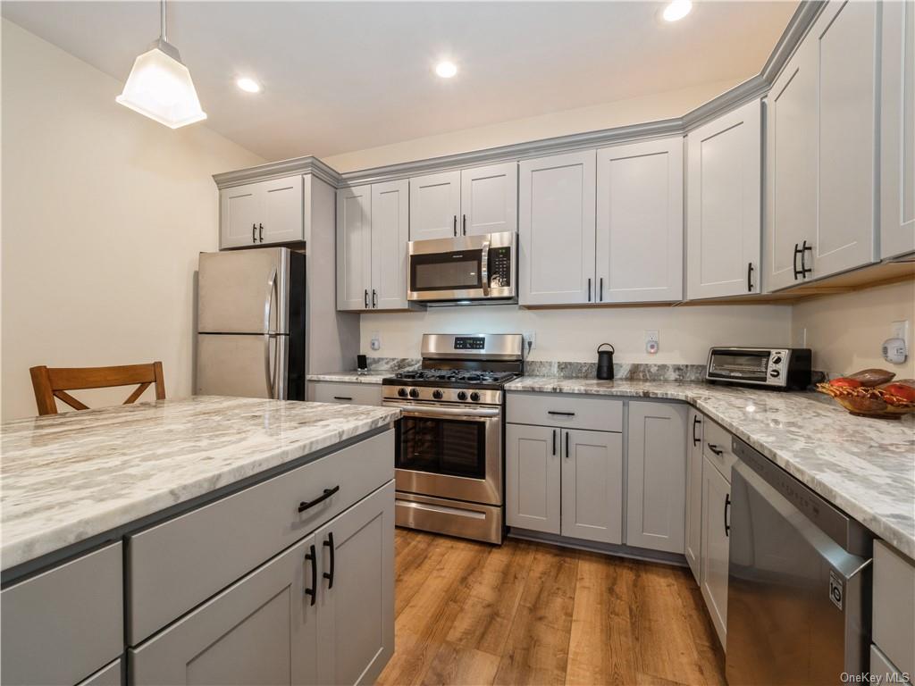 6-8 Wilbur Road Pleasant Valley, NY 12569 - Photo 10 of 36 Kitchen featuring appliances with stainless steel finishes, a kitchen bar, light hardwood / wood-style floors, and light stone countertops