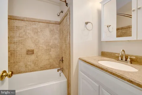 a bathroom with a granite countertop sink mirror toilet and bathtub