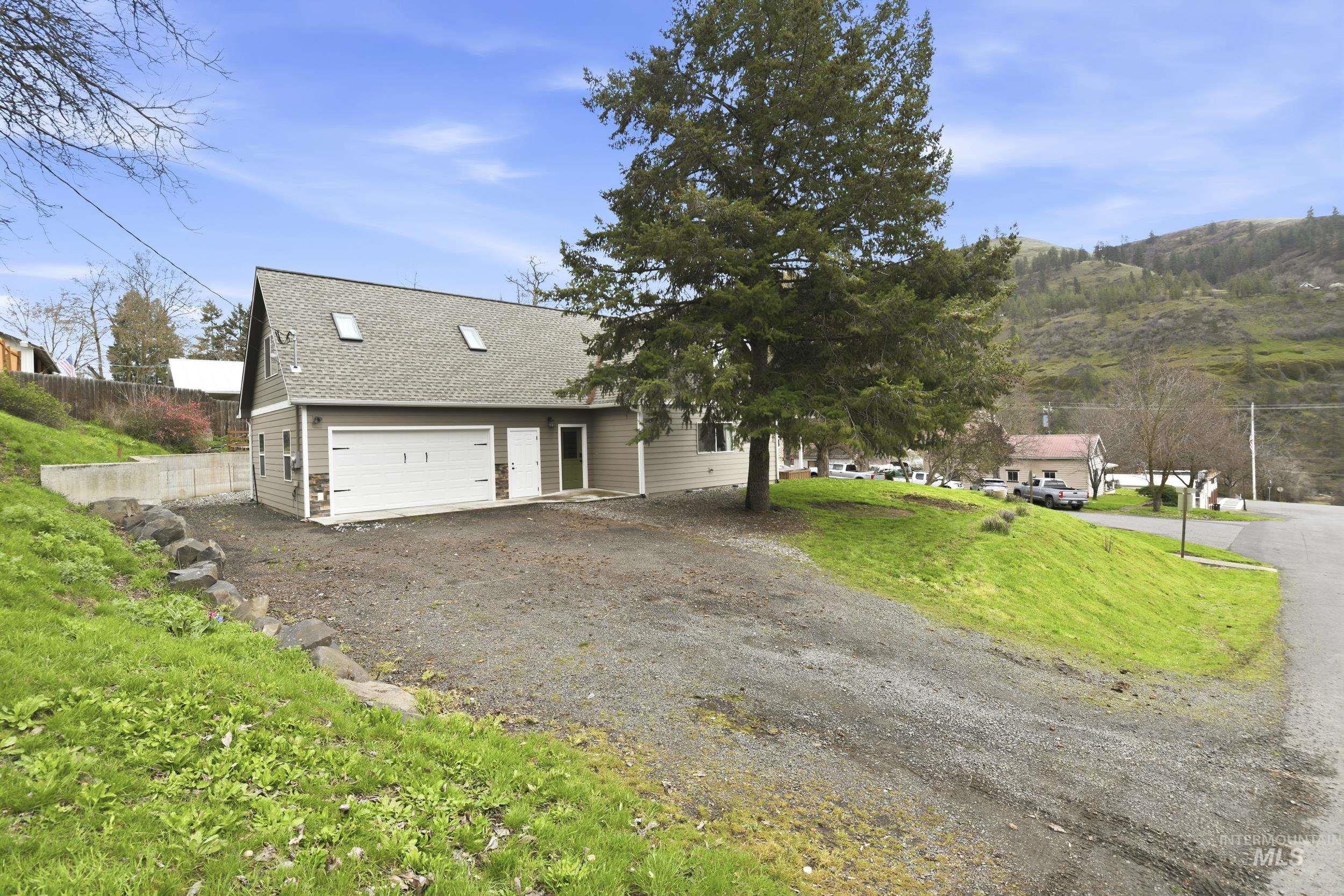 301 State Street Juliaetta, ID 83535 - Photo 34 of 41 View of front of property featuring roof with shingles, dirt driveway, a garage, and a front lawn