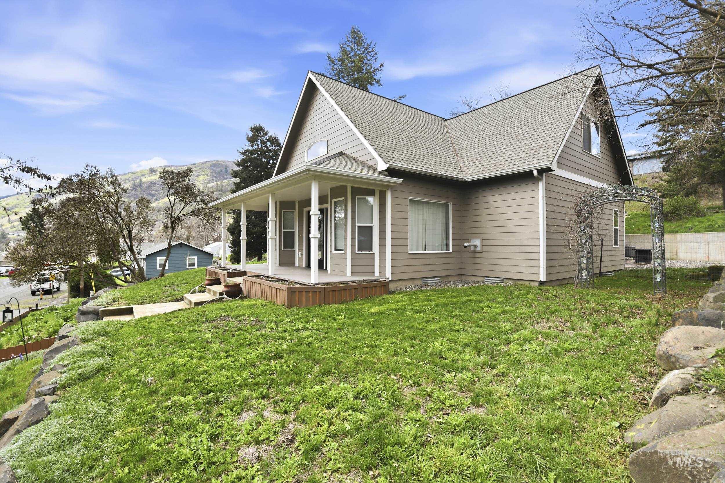 301 State Street Juliaetta, ID 83535 - Photo 5 of 41 View of home's exterior with a shingled roof, a porch, a lawn, and a mountain view