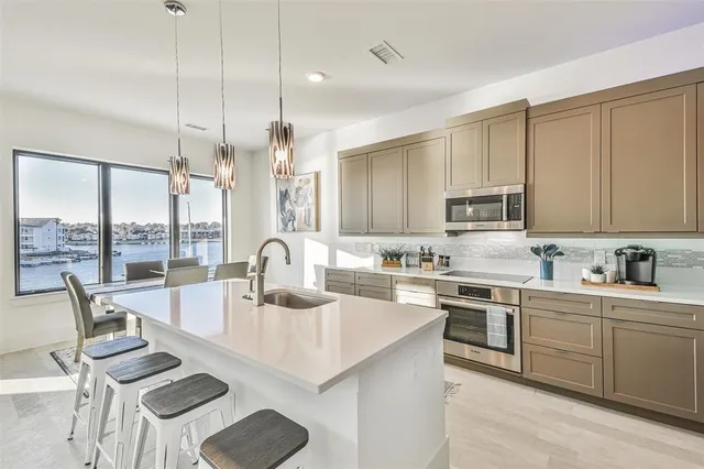 a kitchen with kitchen island granite countertop a table chairs sink and cabinets