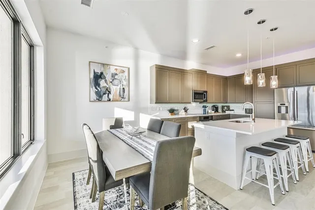 a kitchen with a dining table chairs and refrigerator