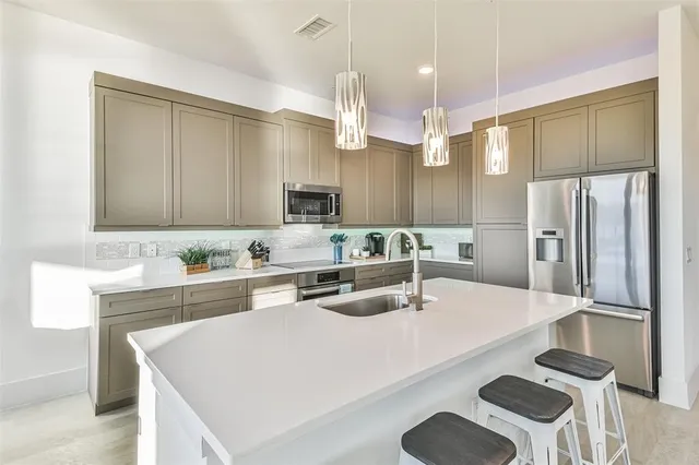 a kitchen with granite countertop a sink a center island stainless steel appliances and cabinets