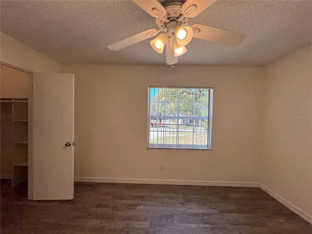 an empty room with wooden floor fan and windows
